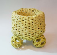 a wicker basket with wheels on a white surface